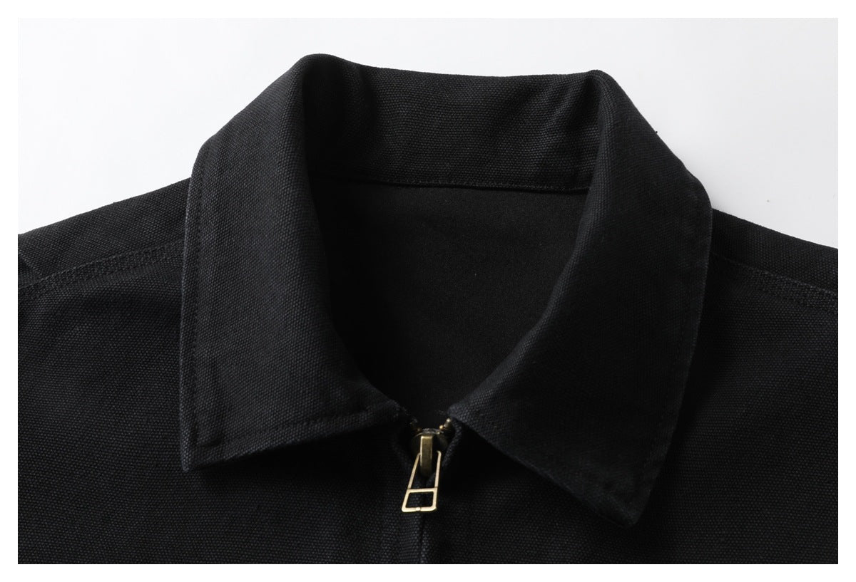 Close-up of a black jacket's pointed collar and front zipper with a brass-tone pull.
