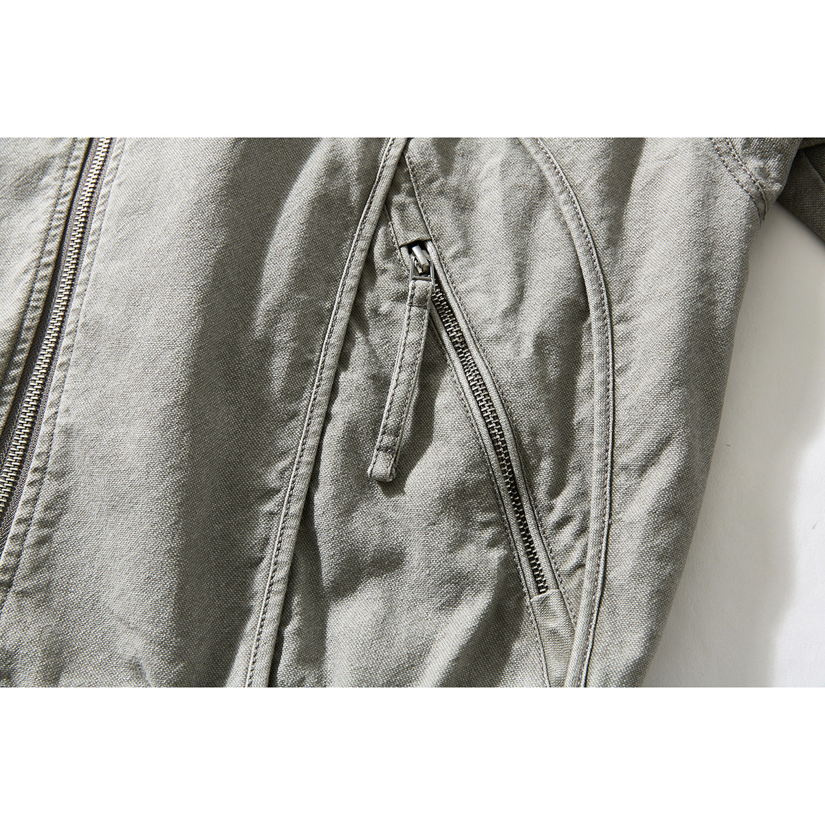 Close-up of a gray washed jacket's angled zip pocket and seams.