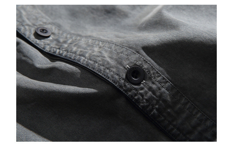 Close-up of a dark garment's button placket with black buttons and visible stitching.