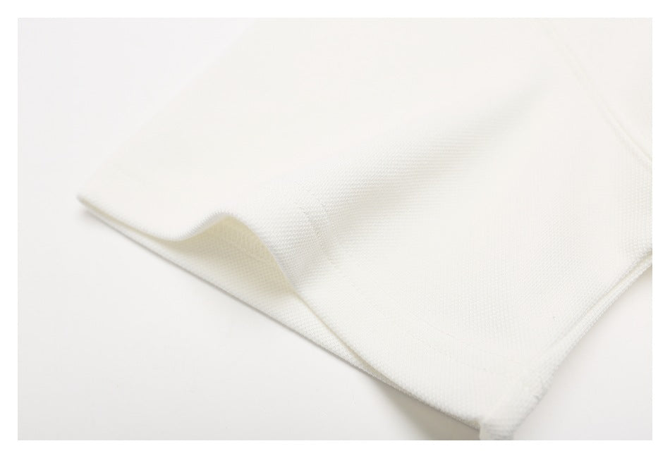 Close-up of off-white polo shirt fabric folded at an edge, showing its textured surface.