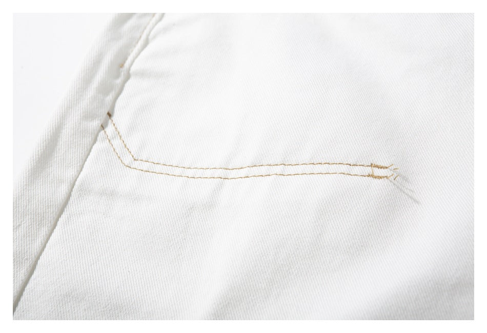 Close-up of a white trouser pocket with tan double stitching.
