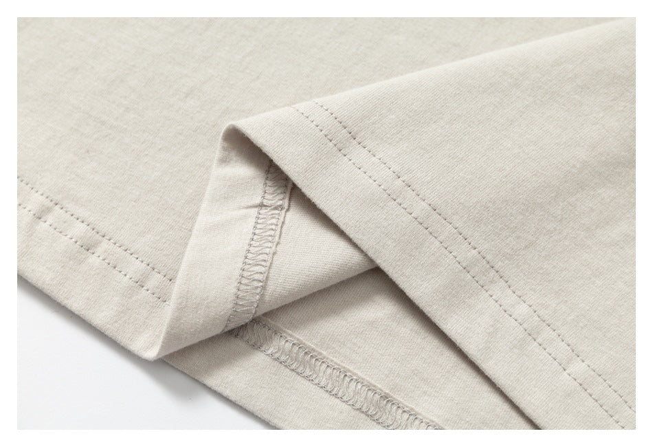 Close-up of the ivory garment's folded hem, showing the stitching and inside seam finish.