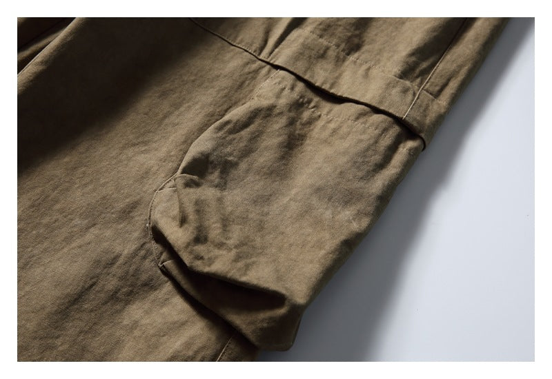 Close-up of olive-brown pants showing a large flap pocket and visible stitching.