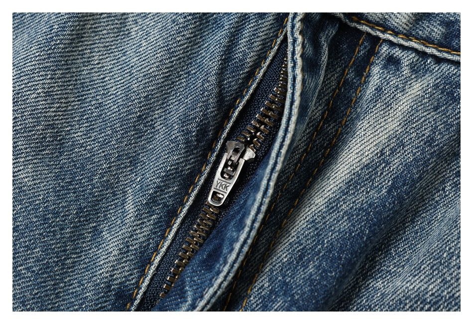 Close-up of a metal YKK zipper on blue faded denim jeans.