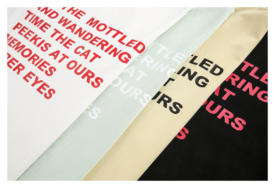 Four folded T-shirts in white, pale mint, light yellow, and black show the same large text print in different colors.