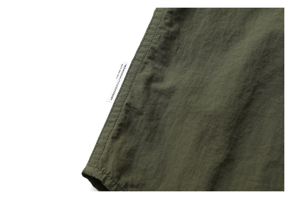 Close-up of the olive-green garment's stitched edge and a small white fabric label.