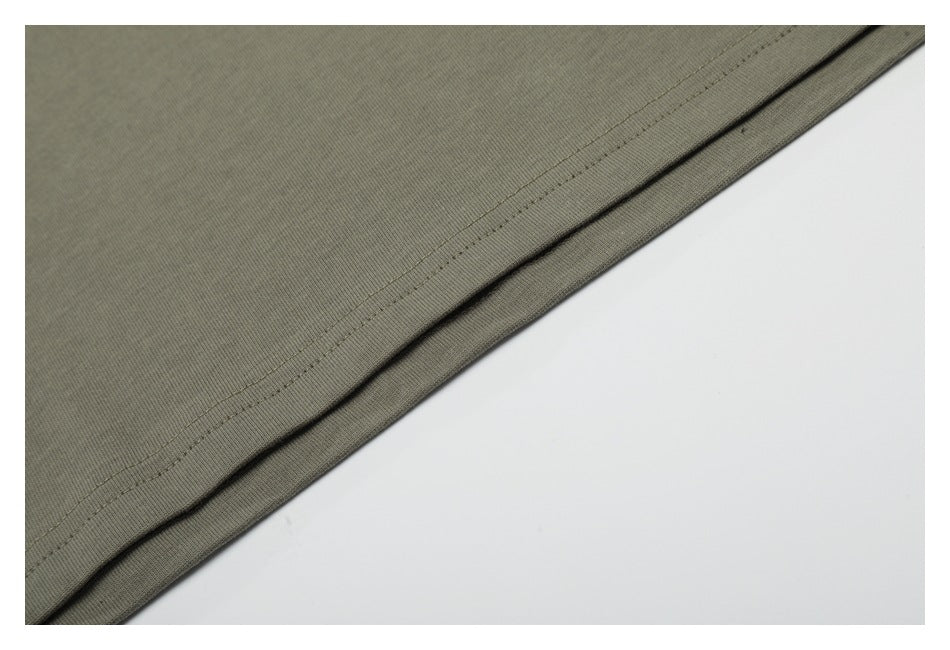 Close-up of the olive-gray garment's folded lower edge and parallel stitching.