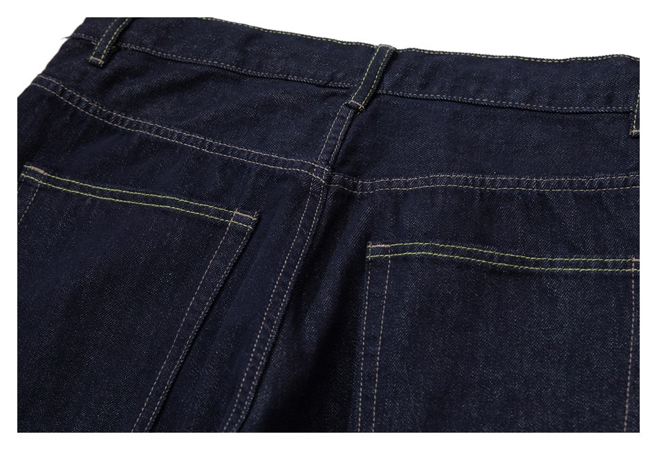 Close view of the back waist and two stitched pockets on dark indigo jeans.