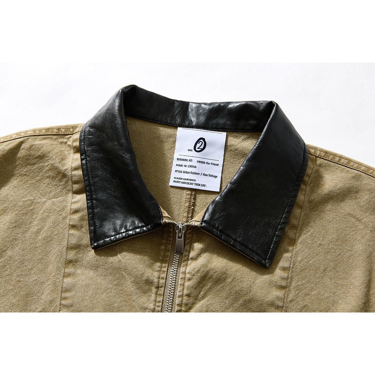 Close-up of a tan jacket with a black leather-look collar, front zipper, and sewn-in neck label.