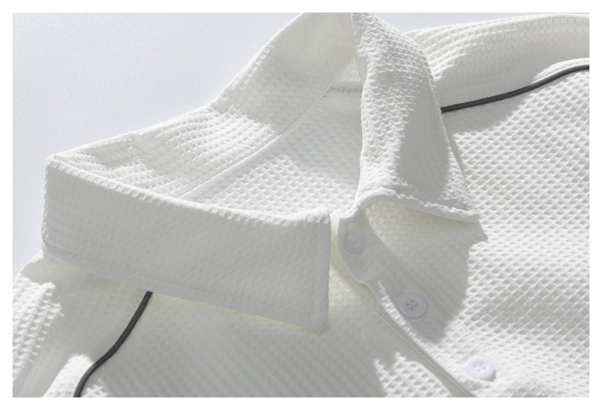 Close-up of a white textured polo shirt collar, three-button placket, and dark piping.
