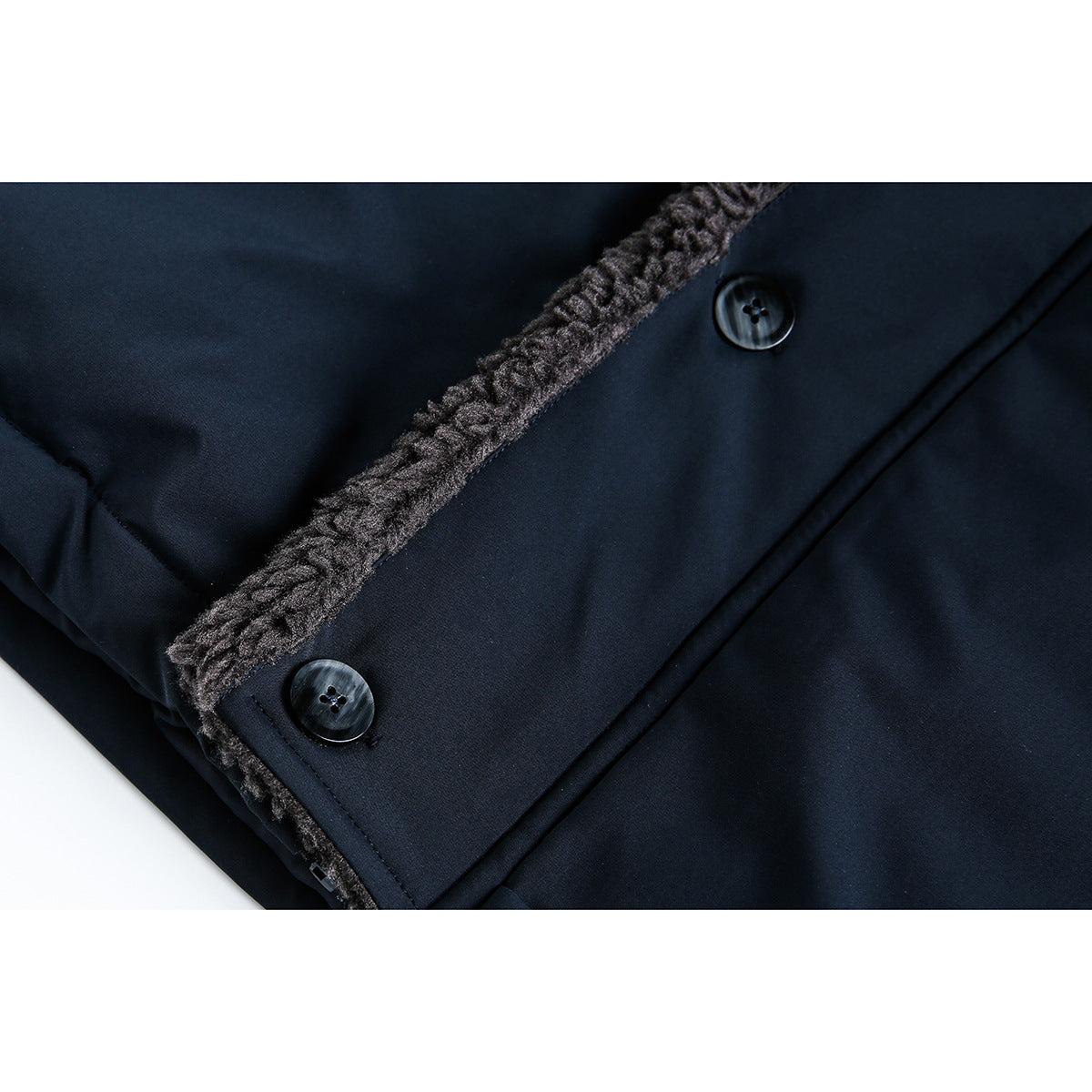 Close-up of a navy coat placket with two dark buttons and a strip of charcoal fuzzy lining.