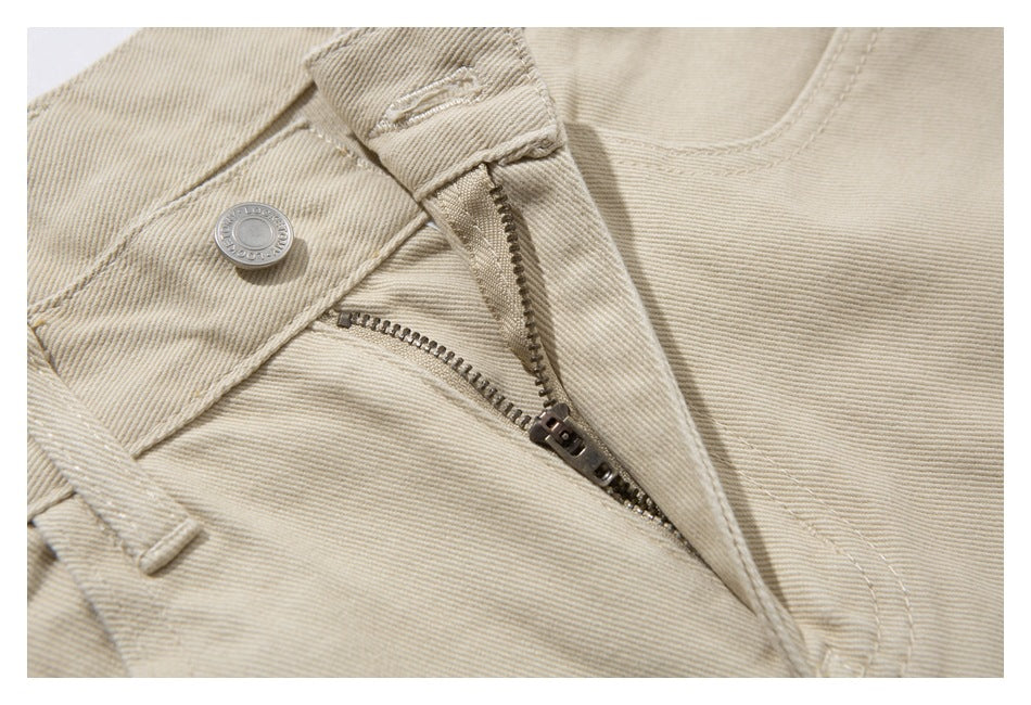Close-up of the open zipper fly and button on beige pants.