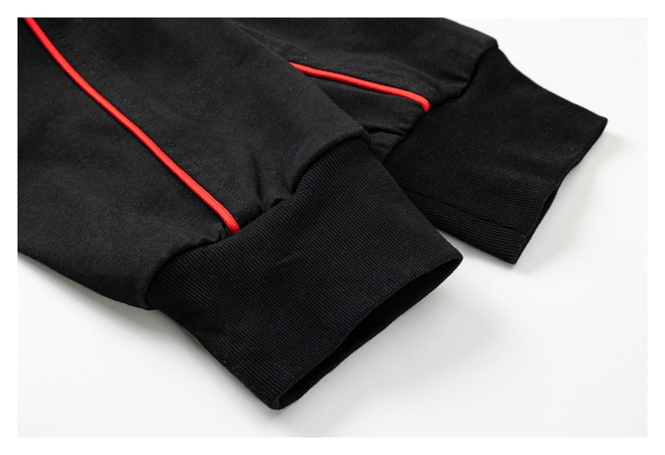 Close-up of ribbed black cuffs and red piping on a black shirt.