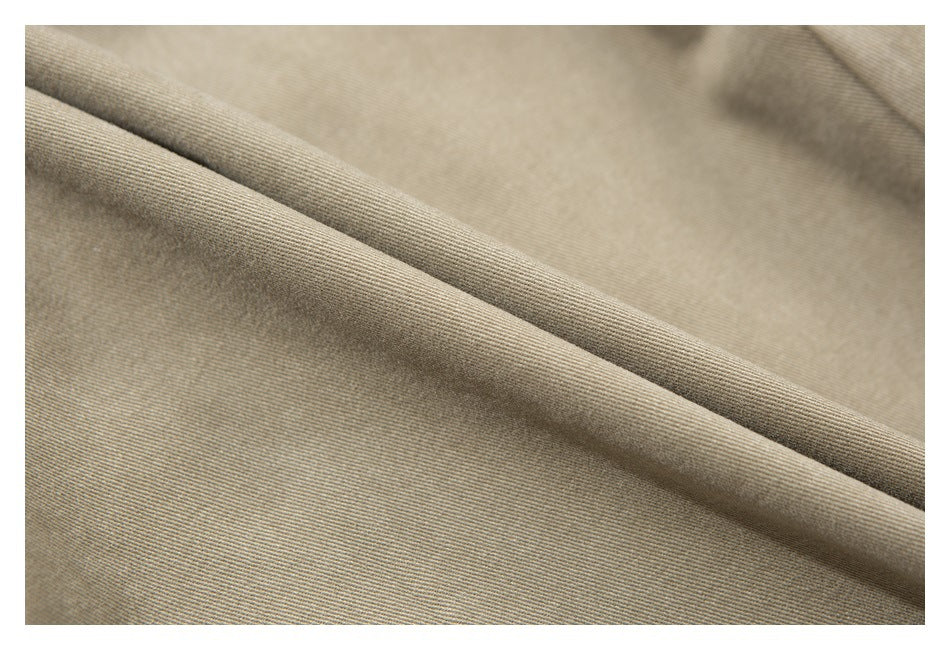 Close-up of khaki fabric folded diagonally, showing its fine woven texture.