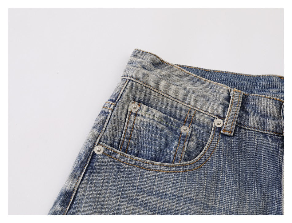 Close-up of faded blue jeans showing the front waistband, belt loop, and riveted coin pocket.