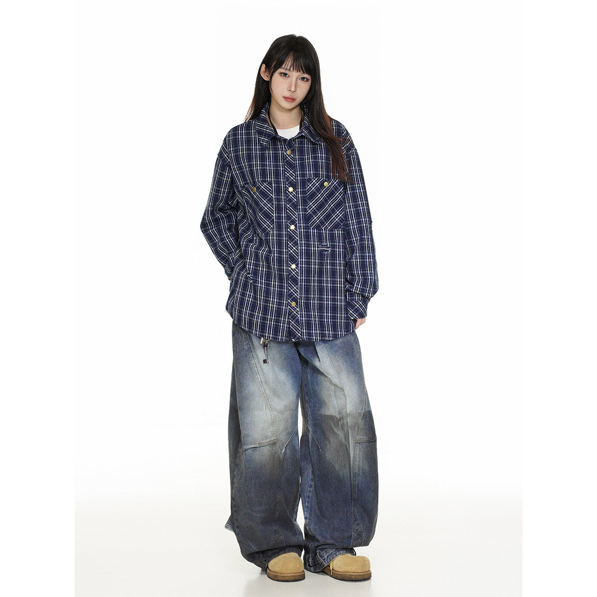 Model wearing an oversized navy plaid button-up shirt with two chest pockets and very wide blue jeans.
