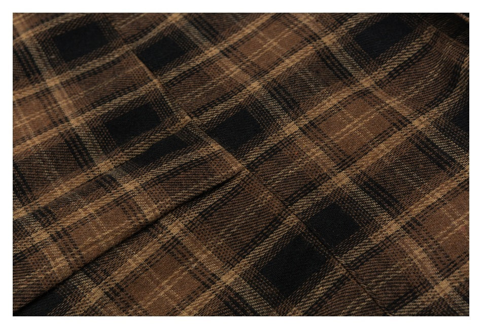 Close-up of brown and black plaid fabric with a woven texture and a soft fold.