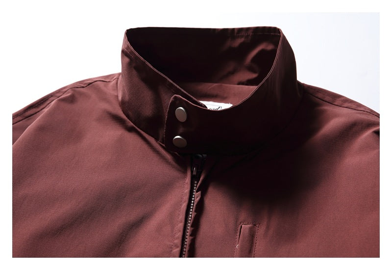 Close-up of a burgundy jacket's tall stand collar, snap buttons, and front zipper.