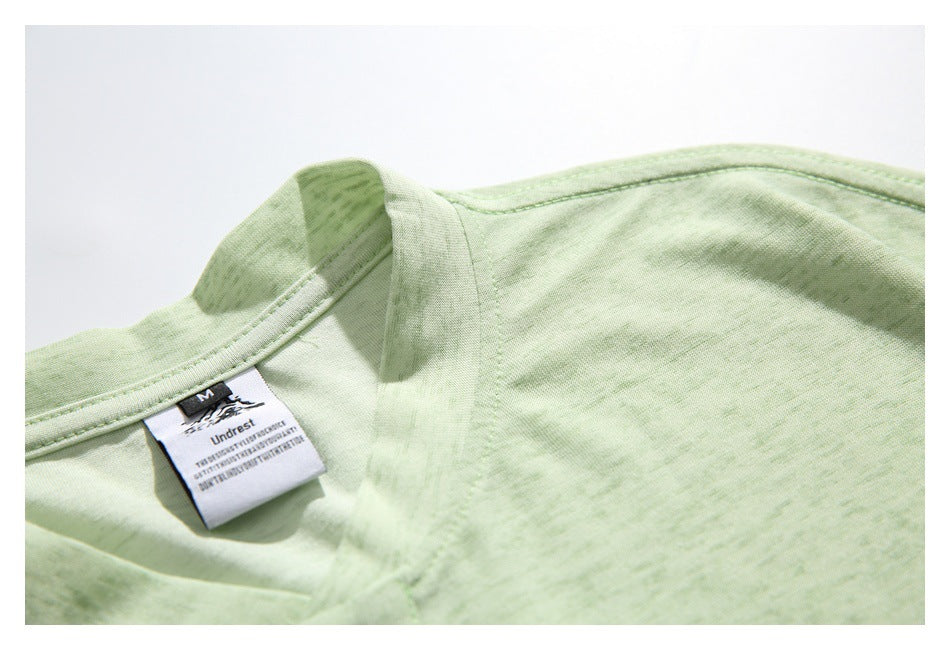 Close-up of the pale green shirt's collar, shoulder seam, and sewn neck label.