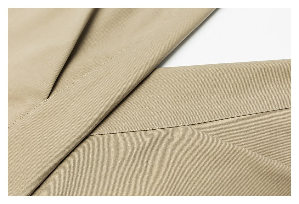 Close-up of beige trouser fabric panels with diagonal seams and fine twill texture.
