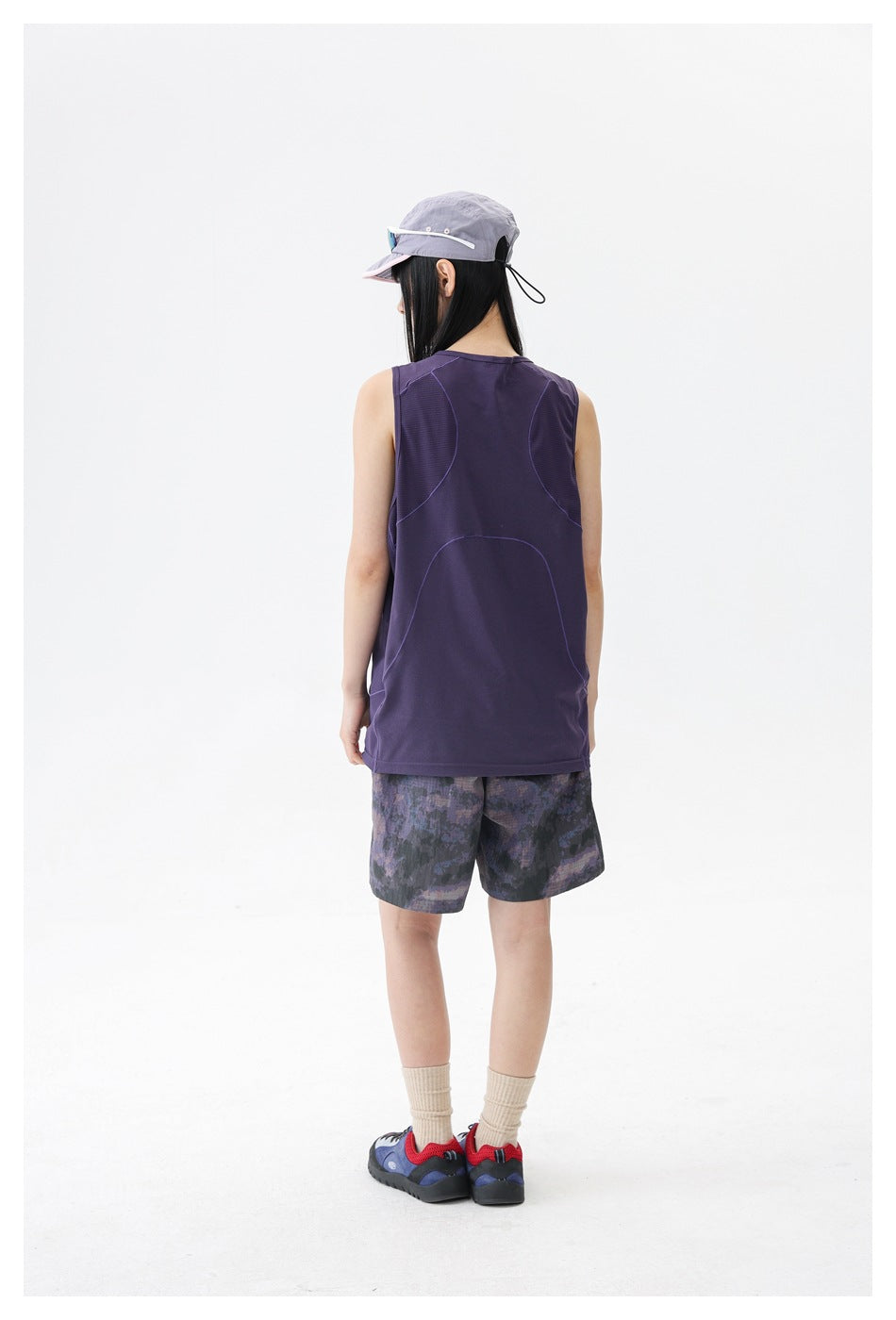 Back view of a model wearing a dark purple sleeveless top and purple-gray patterned shorts.