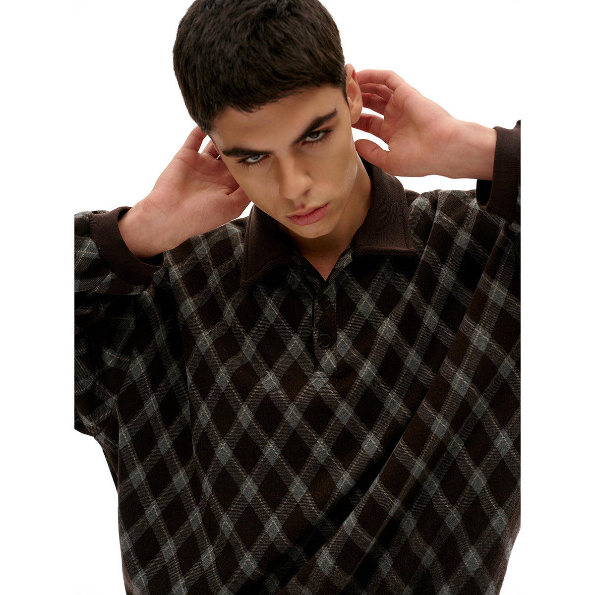 Close-up of a model wearing a dark diamond-check pullover with a dark collar, cuffs, and button placket.