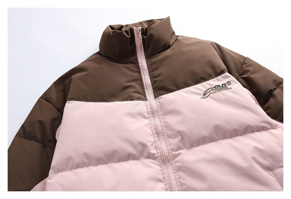 Close-up of a brown and pale pink color-block jacket front with a high collar, pink zipper, and embroidered chest logo.