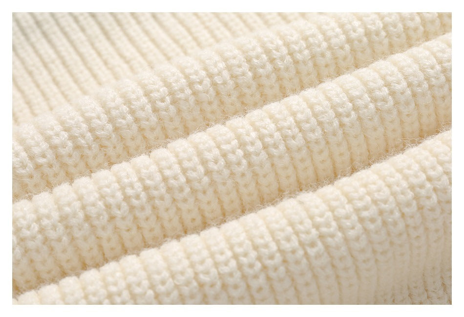 Macro view of the ivory garment’s chunky knitted texture.