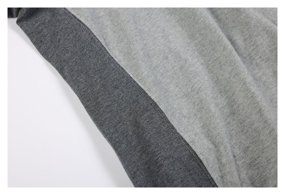 Close-up of a sweatshirt with a light gray body and dark charcoal gray contrast panel, showing the seam.