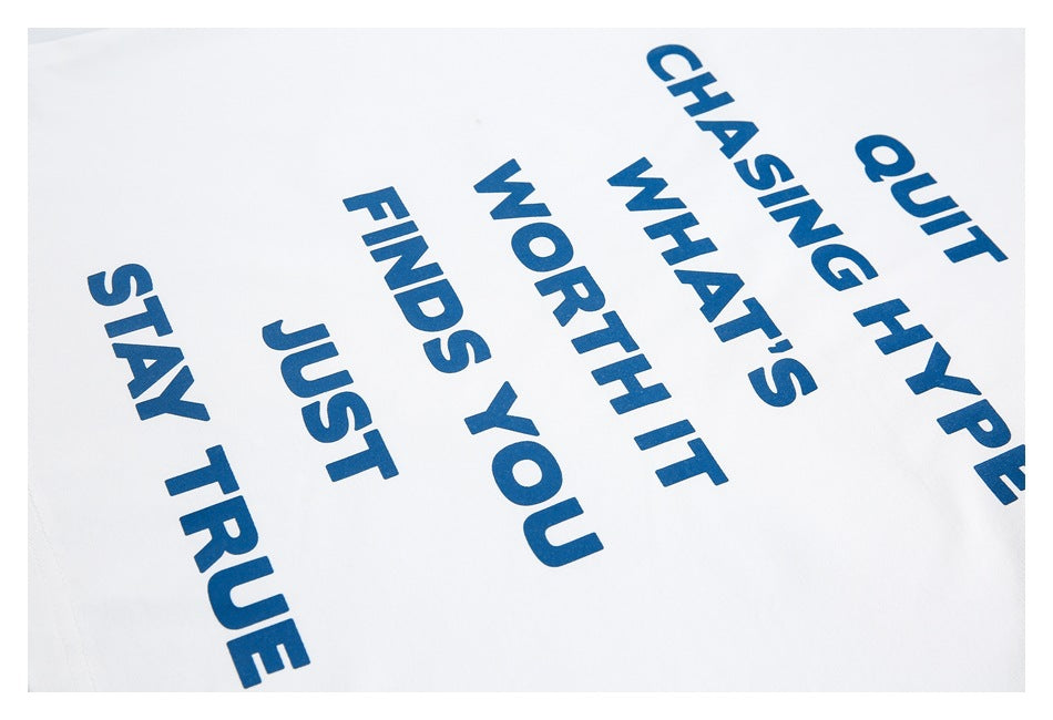 Angled close-up of blue motivational lettering printed on white T-shirt fabric.