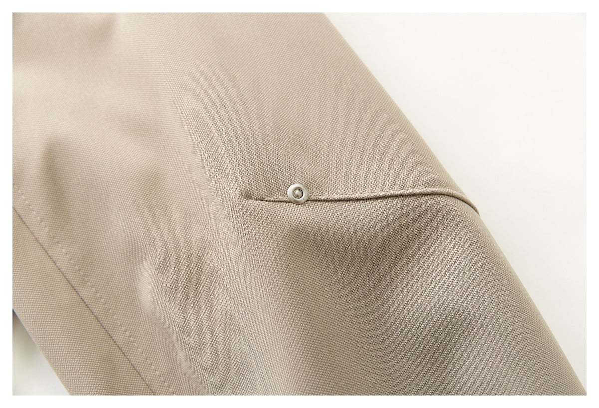Close-up of a beige jacket snap fastening on a stitched flap.