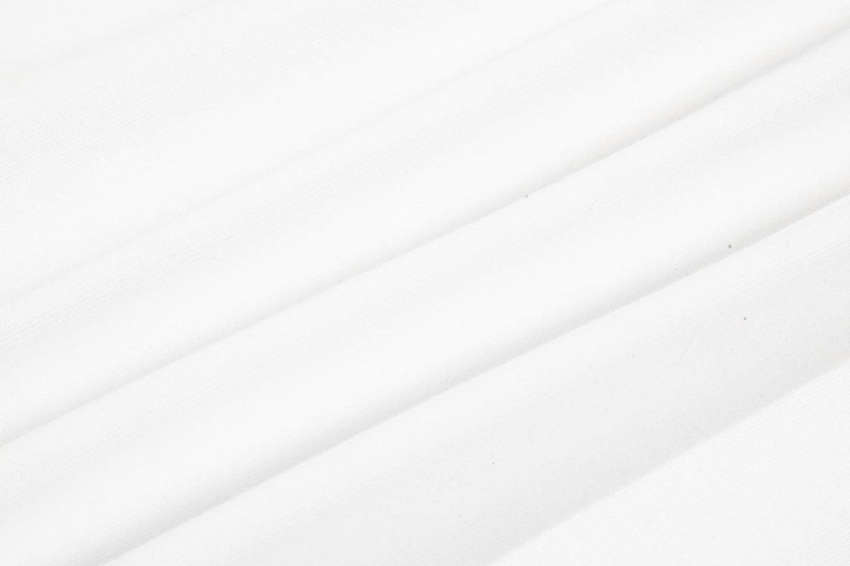 Close-up of white fabric showing a fine textured surface and diagonal folds.
