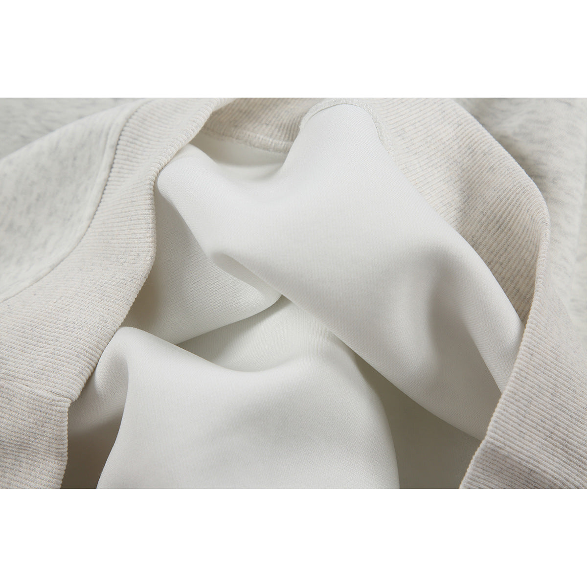 Close-up of the pale fabric and ribbed trim on the inside of a light-colored pullover.