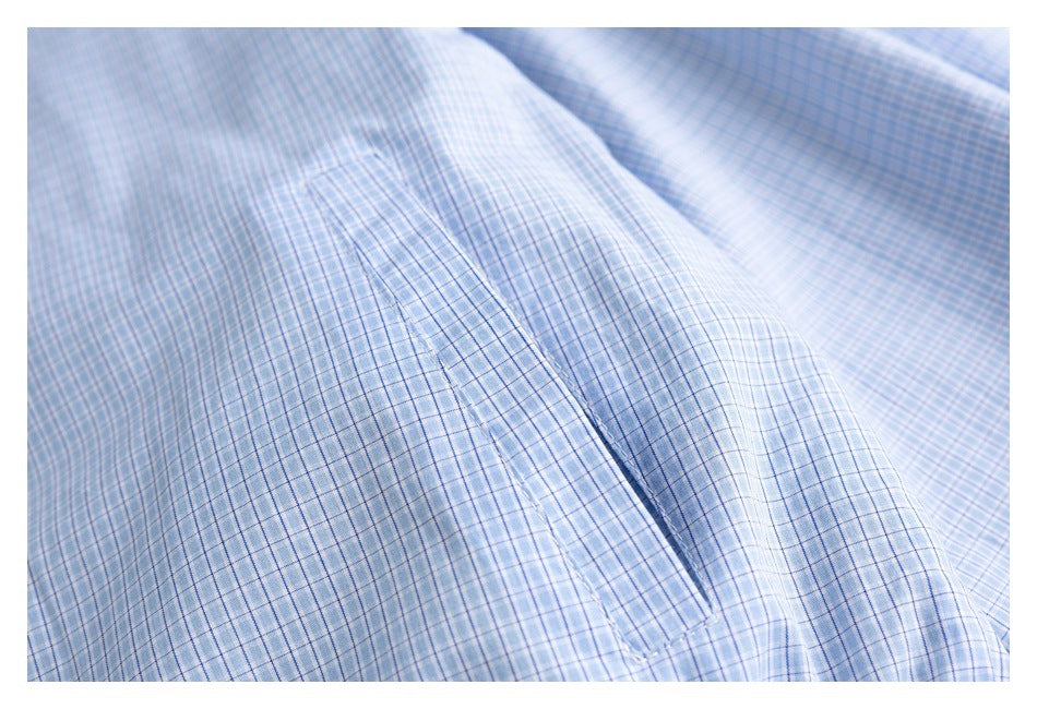 Close-up of a narrow pocket opening and stitching on light blue plaid fabric.