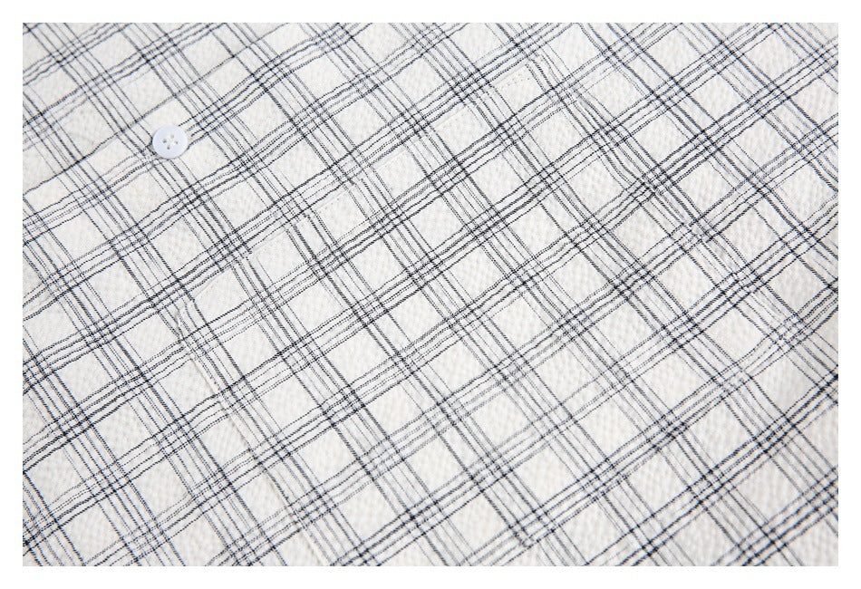 Close-up of ivory plaid shirt fabric with a white button.