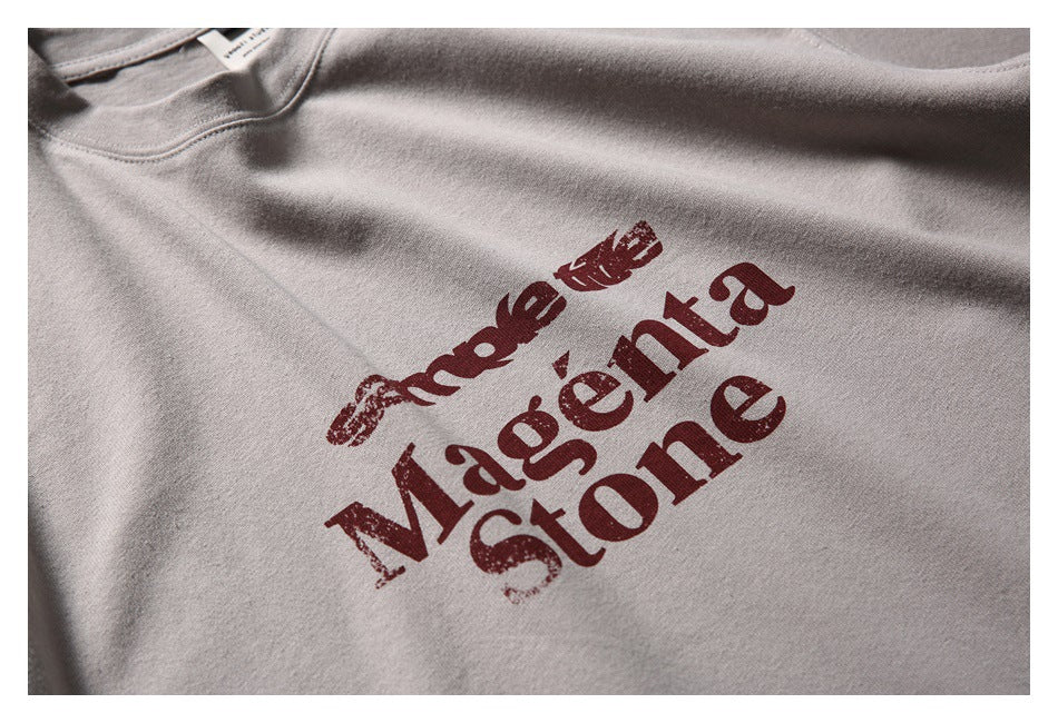 Close-up of a taupe-gray T-shirt with a distressed burgundy lettering graphic.