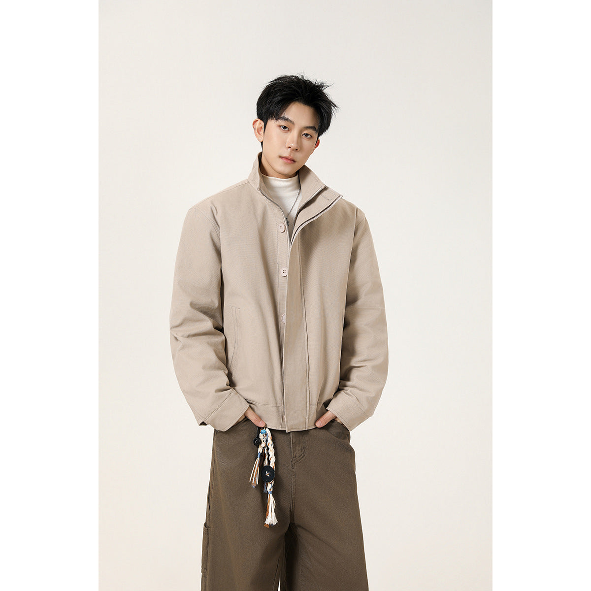 Model wearing a light beige stand-collar jacket with a buttoned front and concealed zipper.