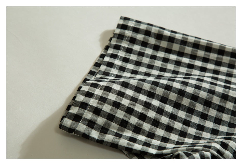 Close-up of folded black-and-white gingham fabric with a stitched edge.