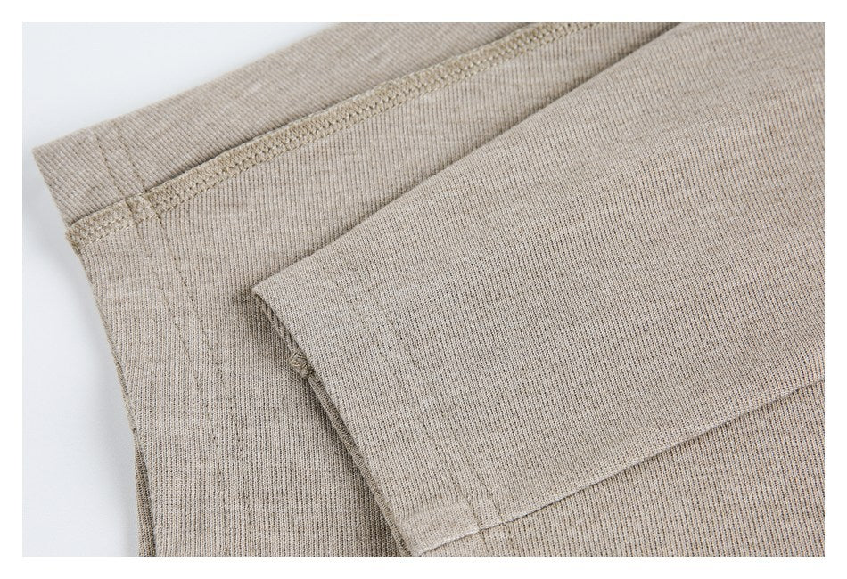 Close-up of folded taupe knit fabric showing garment hems and stitched seams.