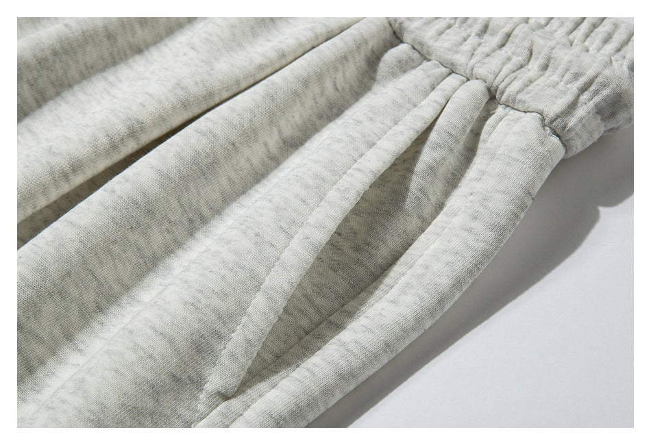 Close-up of light heather-gray sweatpants with an elastic waistband and gathered fabric folds.