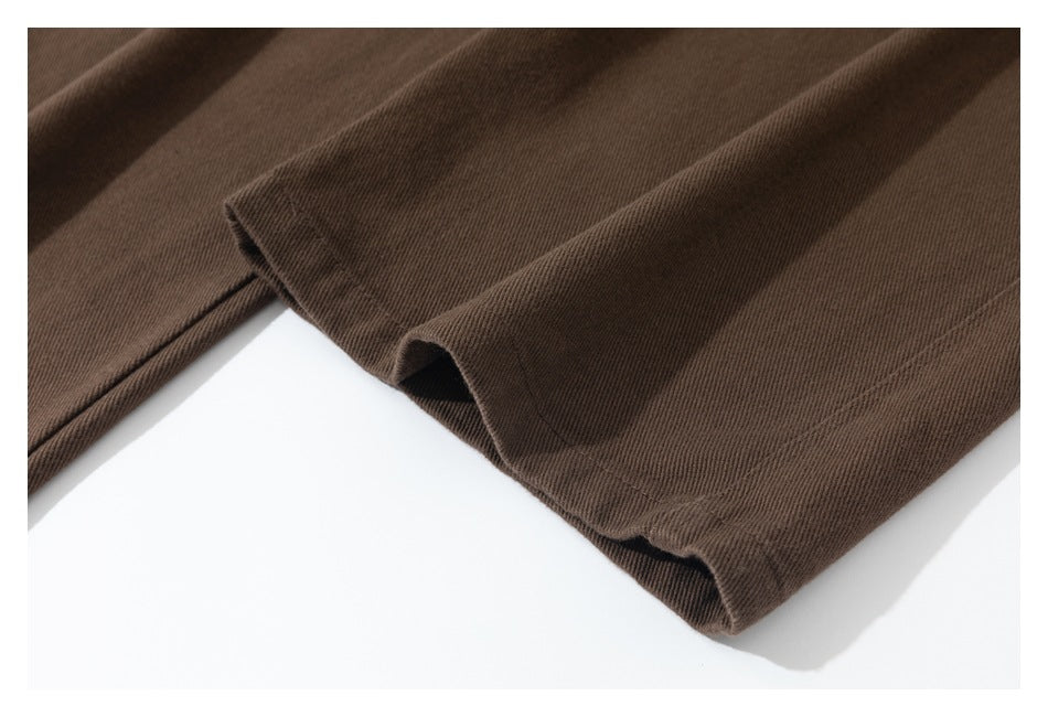 Close-up of brown trouser leg hems with visible stitching and folded fabric edges.