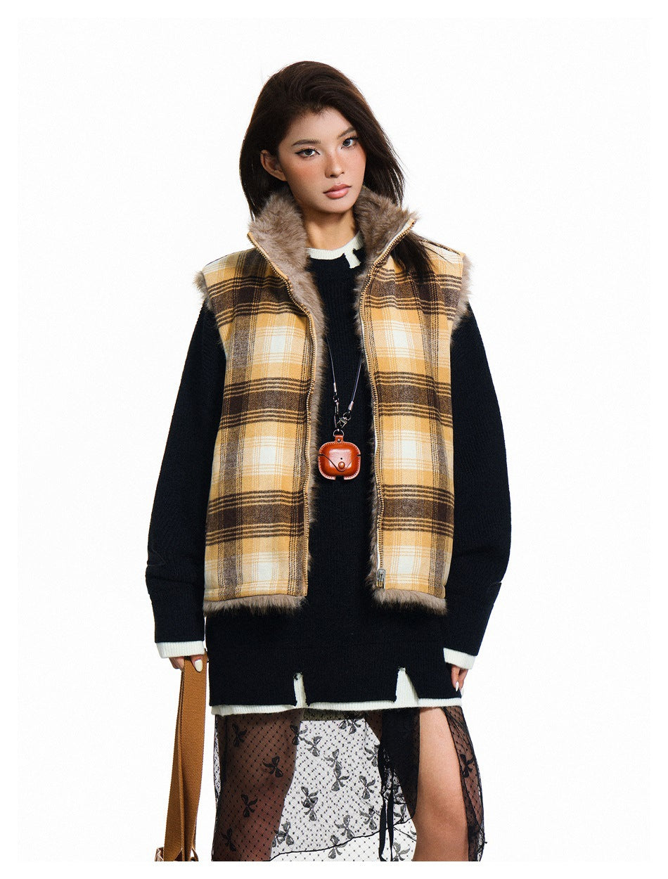 Model wearing a yellow, cream, and brown plaid vest with fur trim over a black sweater and patterned skirt.