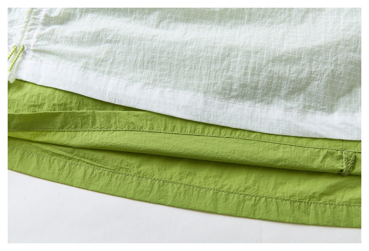 Close-up of the skirt's pale green grid-patterned outer layer over a solid lime-green hem and stitched seam.