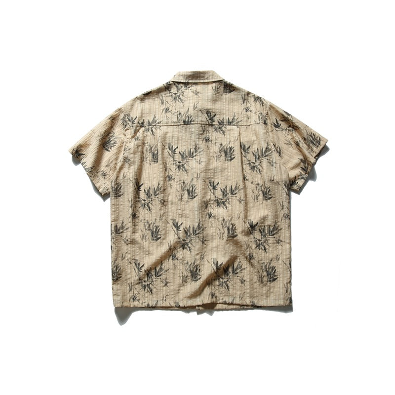 Back view of khaki short-sleeve shirt with gray bamboo leaf print and back yoke, flat lay