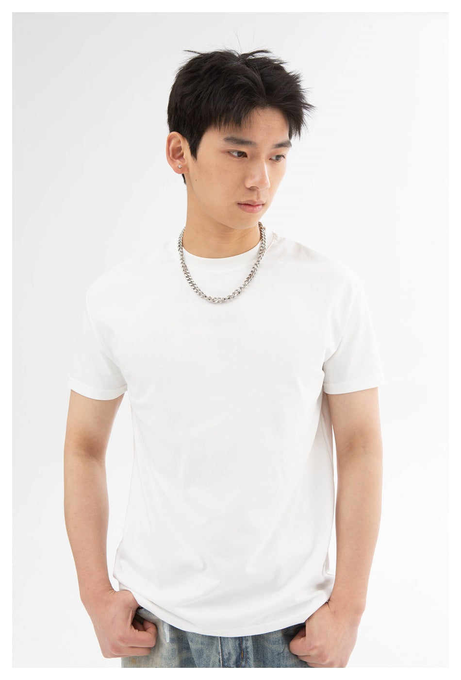 Close view of a model wearing a plain white crew-neck T-shirt, with a silver chain necklace.