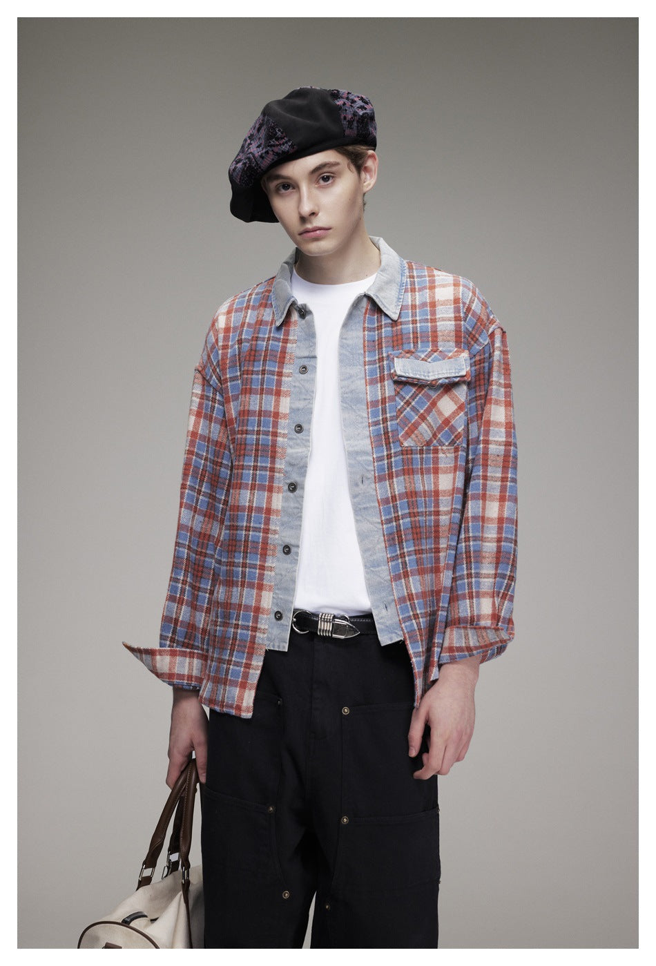 Front view of a model wearing a blue, rust and cream plaid overshirt with a pale collar and flap chest pocket.