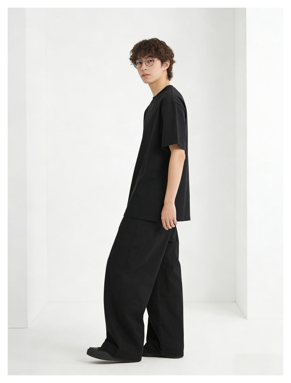 Model wearing a black short-sleeve T-shirt and loose black wide-leg pants, shown in a side-facing pose.