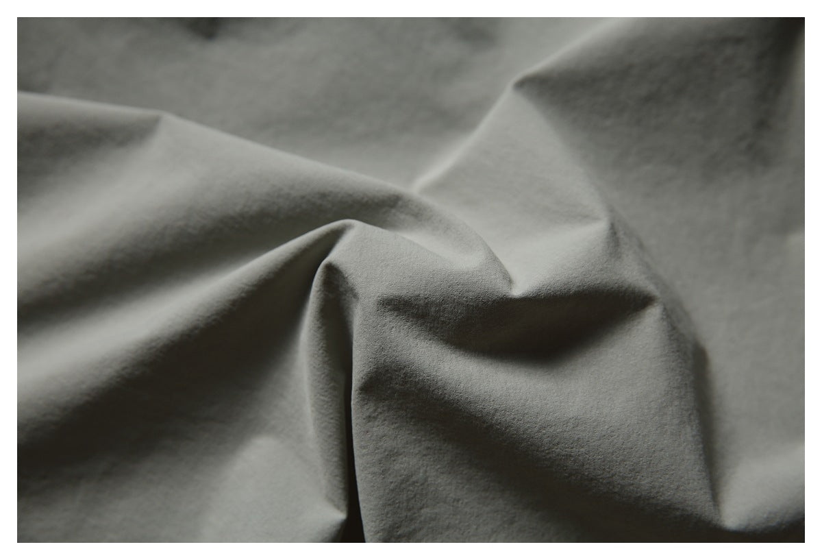 Close-up of gray garment fabric arranged in soft folds.
