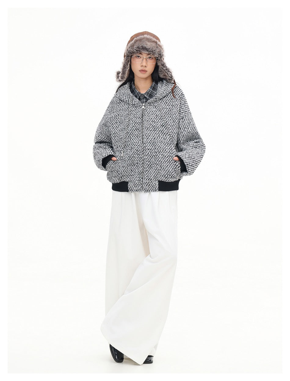 Full-length front view of a model wearing a zipped black-and-white textured hooded jacket with dark ribbed cuffs and hem.