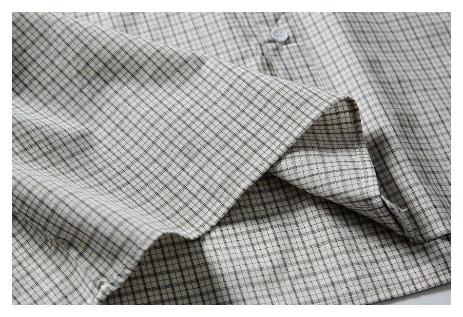 Close-up of the pointed collar and front of an off-white shirt with a fine black and gray check pattern.